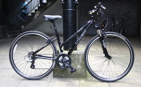 a black bicycle parked on a sidewalk