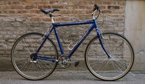 a blue bicycle parked next to a brick wall