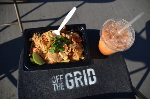 a black rectangular container with food in it and a plastic cup with a straw