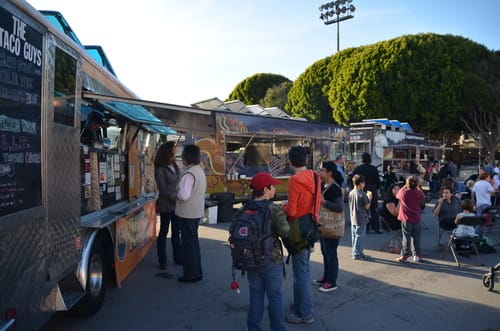 a group of people standing next to a food truck