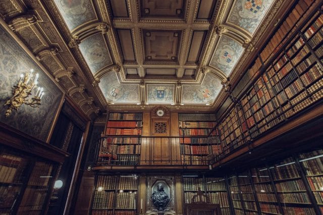a large ornate room with a large ceiling and a large staircase with Morgan Library & Museum in the background
