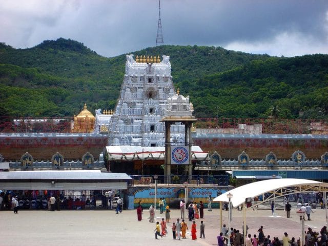 a large building with a dome and a hill in the background with Venkateswara Temple, Tirumala in the background