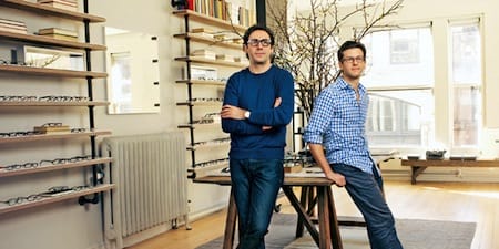 a couple of men posing for a picture in a room with shelves